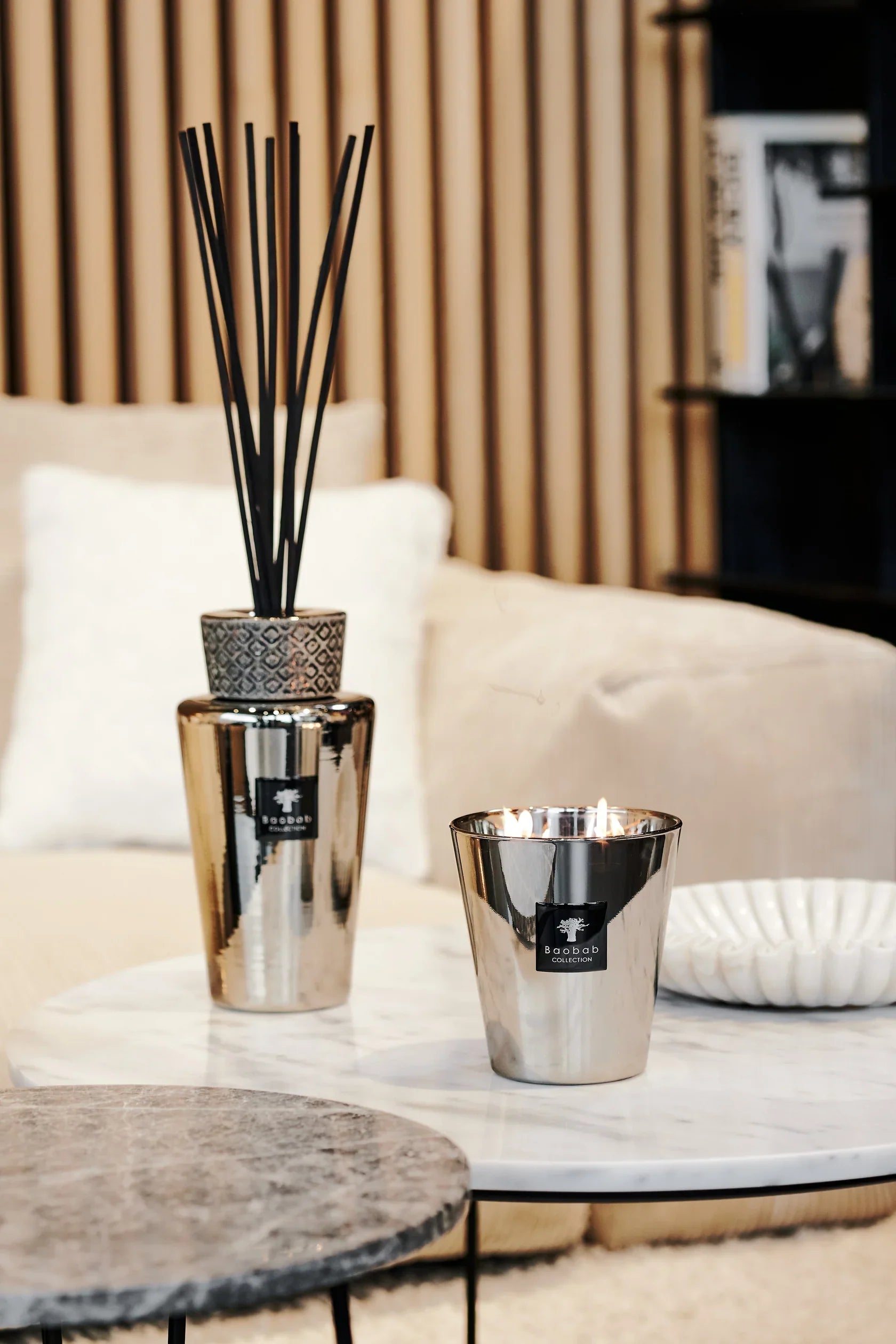 Baobab Collection TOTEM Platinum diffuser and candle on a marble table in a cozy interior setting.