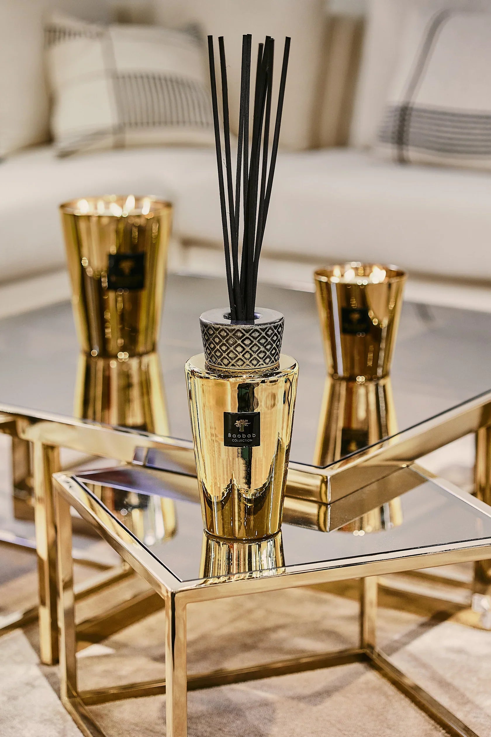 Baobab Collection TOTEM AURUM fragrance diffuser with black sticks on a reflective coffee table.