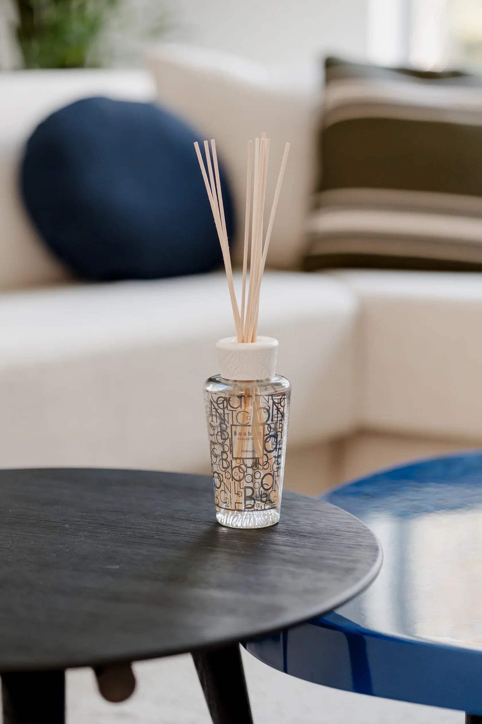 Baobab Collection My First Baobab Platinum diffuser on a table, featuring reed sticks and a stylish design.