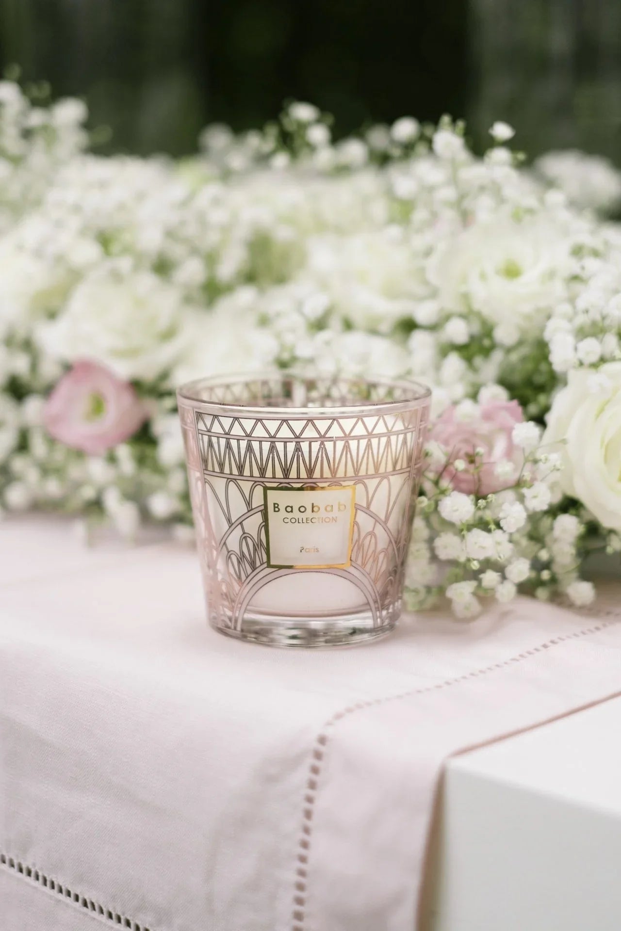 Baobab Collection pink scented candle with floral background, featuring Eiffel Tower design, perfect for celebrating Parisian spring.