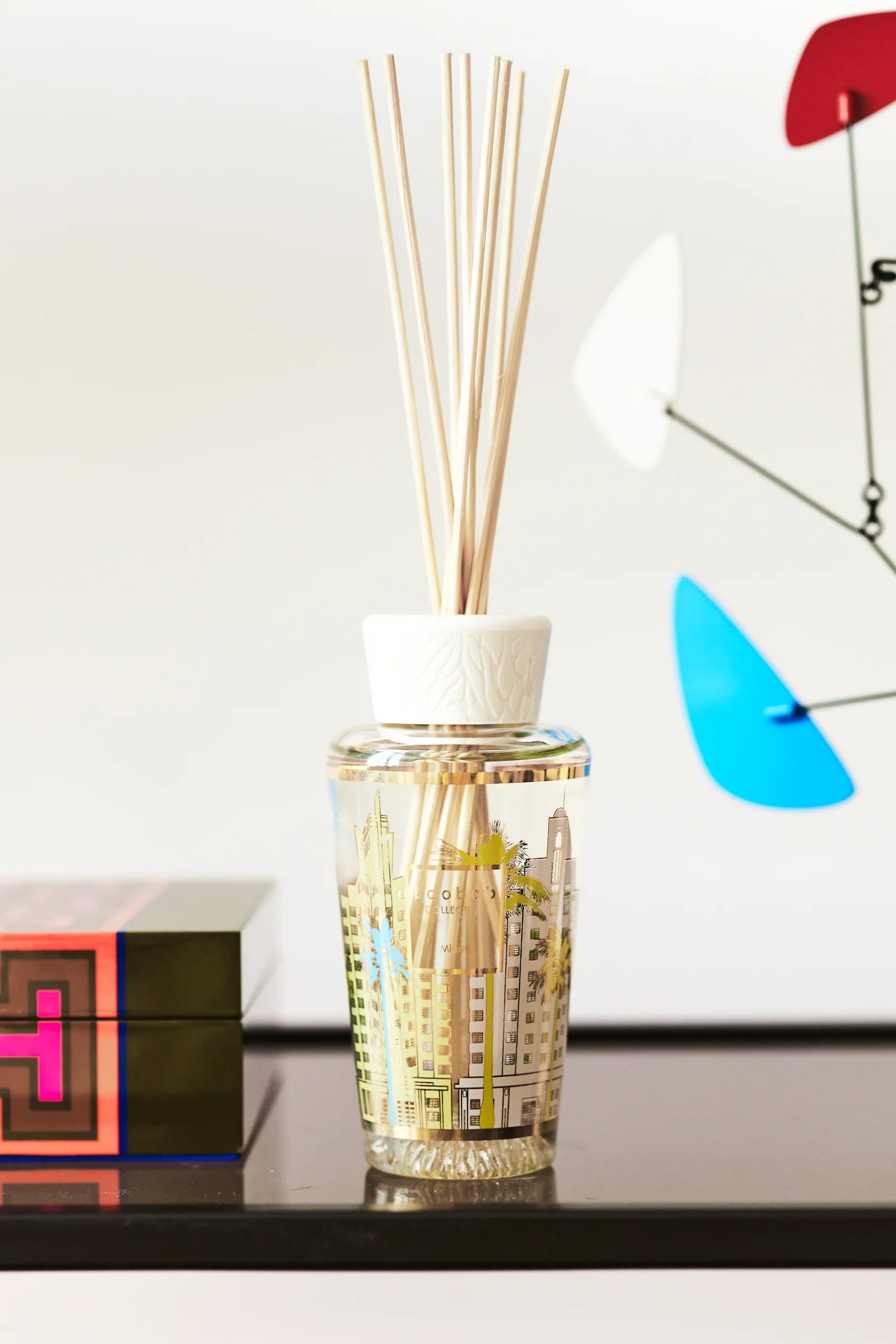 Baobab Collection My First Baobab Miami diffuser with pastel gold design, showcasing art deco architecture and reed sticks.
