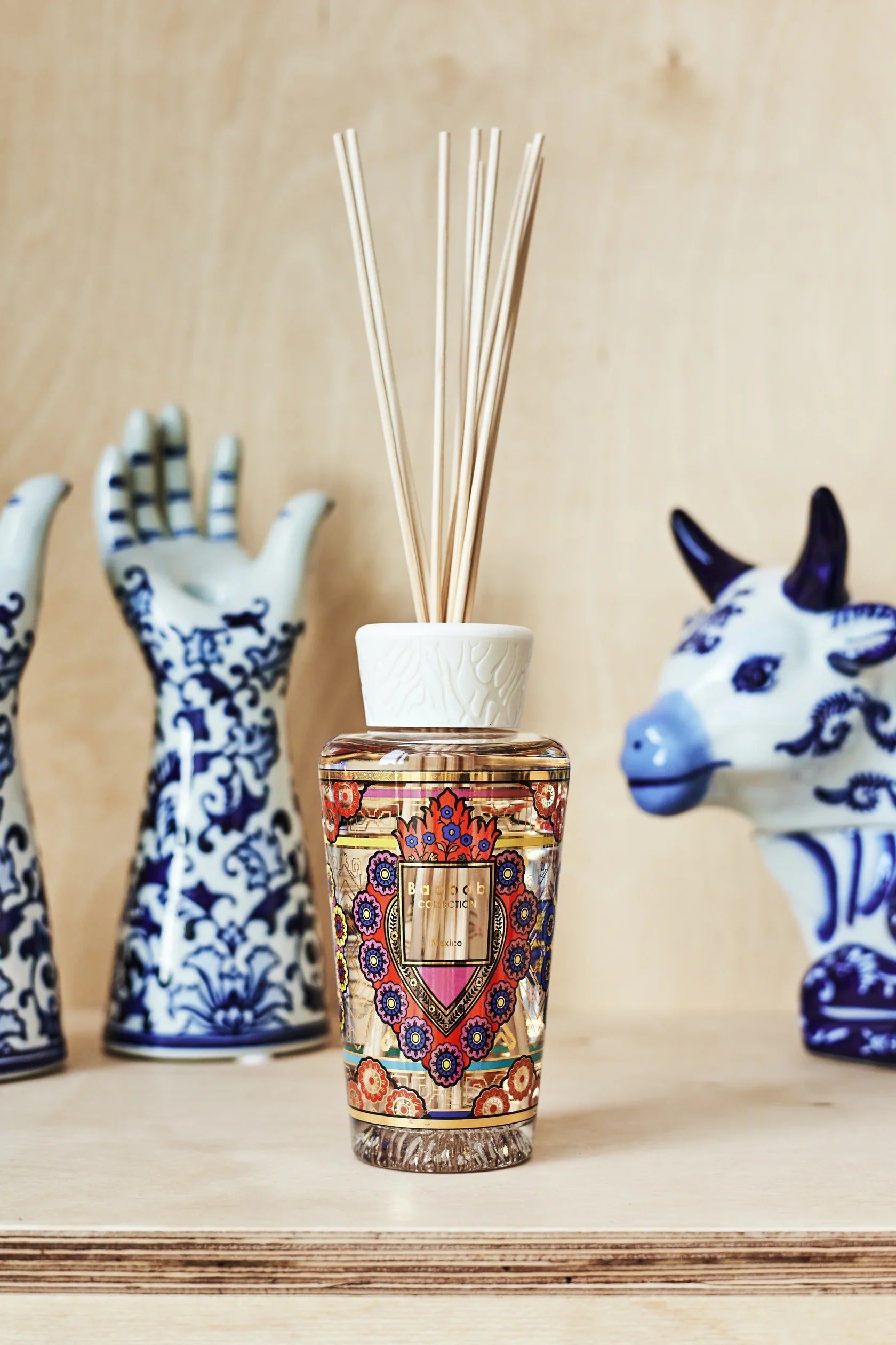Baobab Collection My First Baobab diffuser with colorful ex-voto heart design and aromatic reeds, surrounded by decorative ceramics.