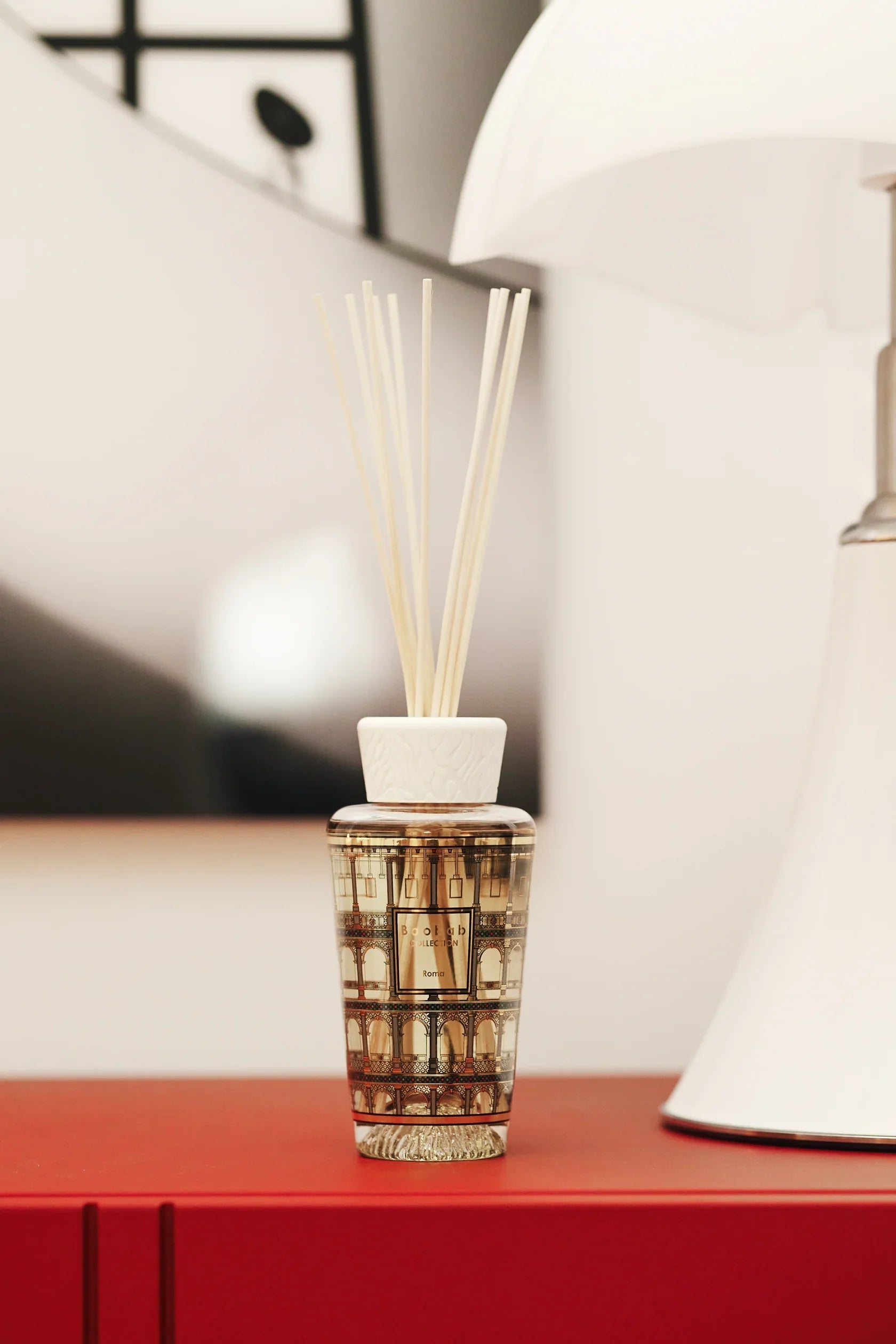 Baobab Collection My First Baobab Roma diffuser showcasing gold detailing and fragrance reeds on a red surface.