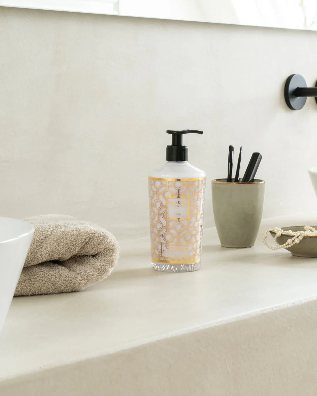 Baobab Collection body and hand lotion in an elegant bottle with gold design, displayed in a stylish bathroom setting.