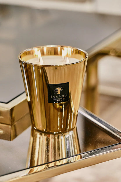 Baobab Collection Aurum scented candle in gold glass on reflective surface, showcasing elegance and luxury.