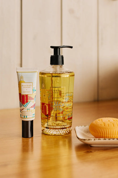 Baobab Collection hand wash gel and moisturizing cream, with gold design inspired by Saint-Tropez on a wooden table.