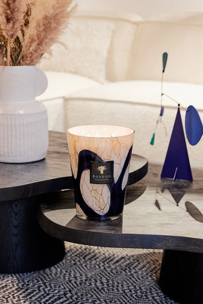 Scented candle in marbled glass with blue patterns, showcasing elegance and sophistication in a stylish living room setting.