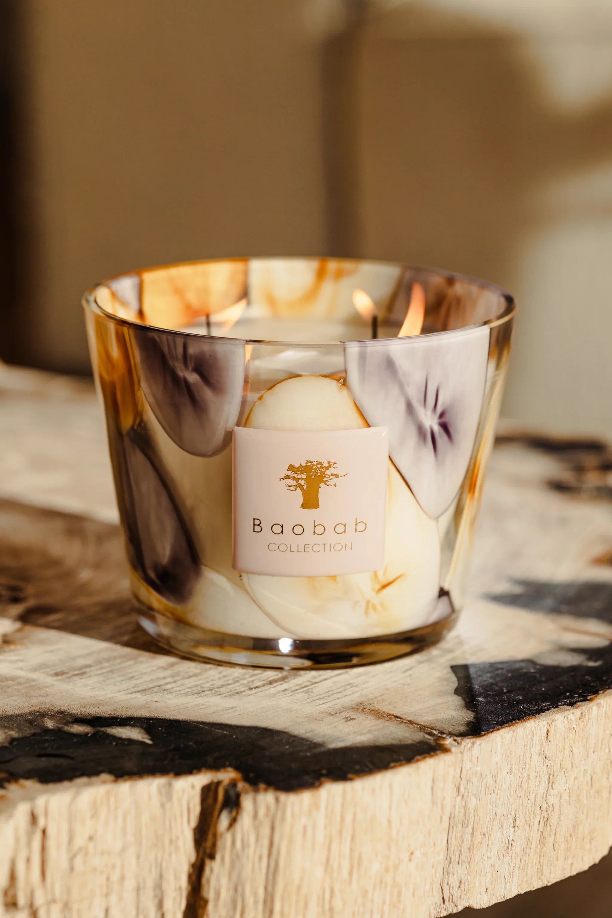 Baobab Collection Eilenroc scented candle in mauve and saffron glass on a wooden surface.