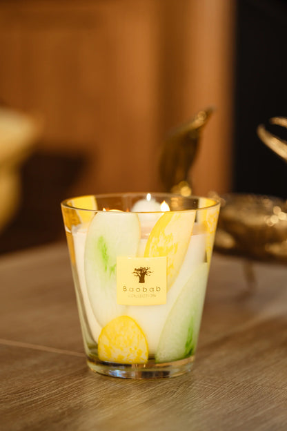 Baobab Collection scented candle in hand-blown glass with vibrant green and yellow designs, showcasing artisanal craftsmanship.