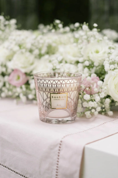 Baobab Collection pink scented candle with floral background, featuring Eiffel Tower design, perfect for celebrating Parisian spring.