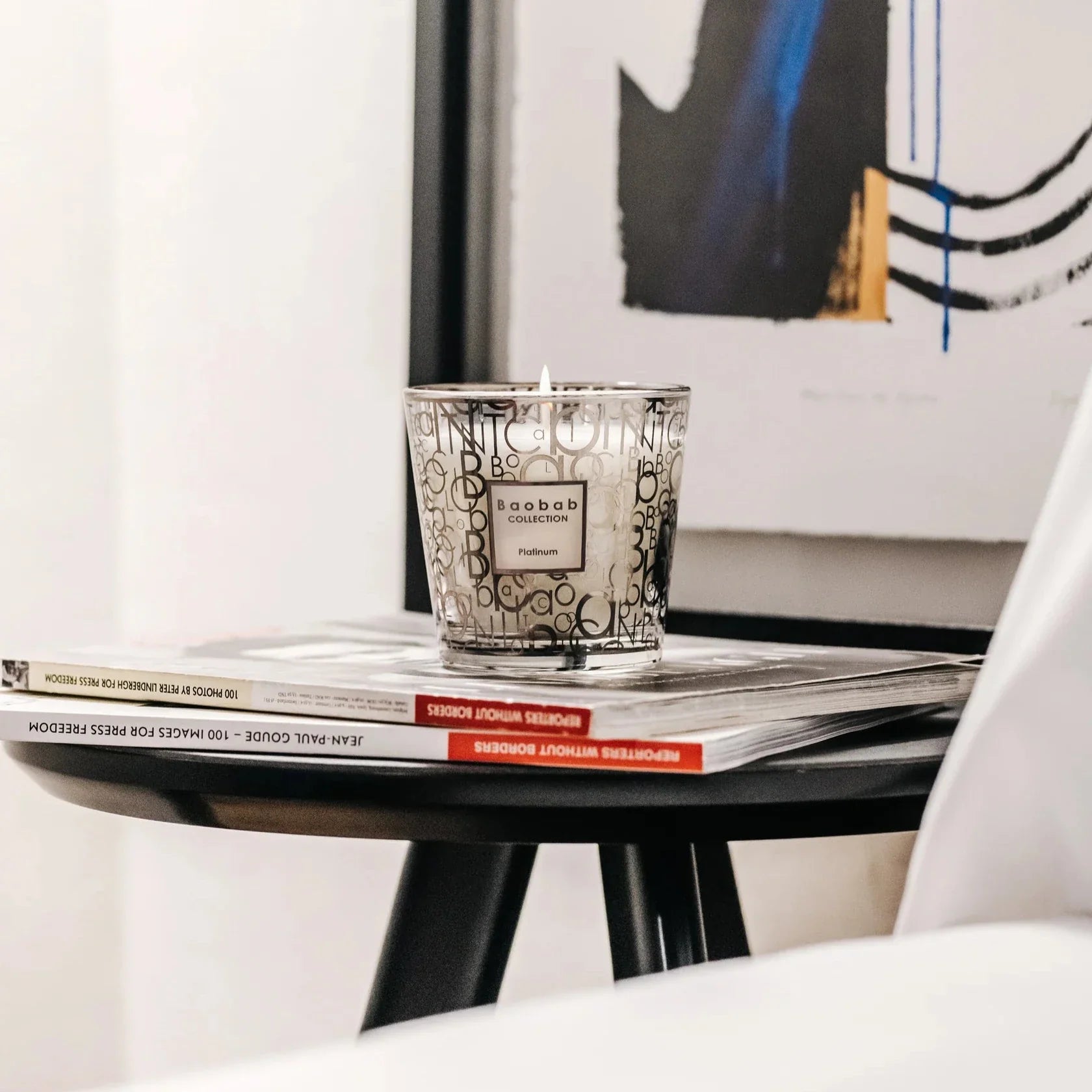 Baobab Collection scented candle 'My First Baobab Platinum' on a coffee table, showcasing its elegant design and glow.