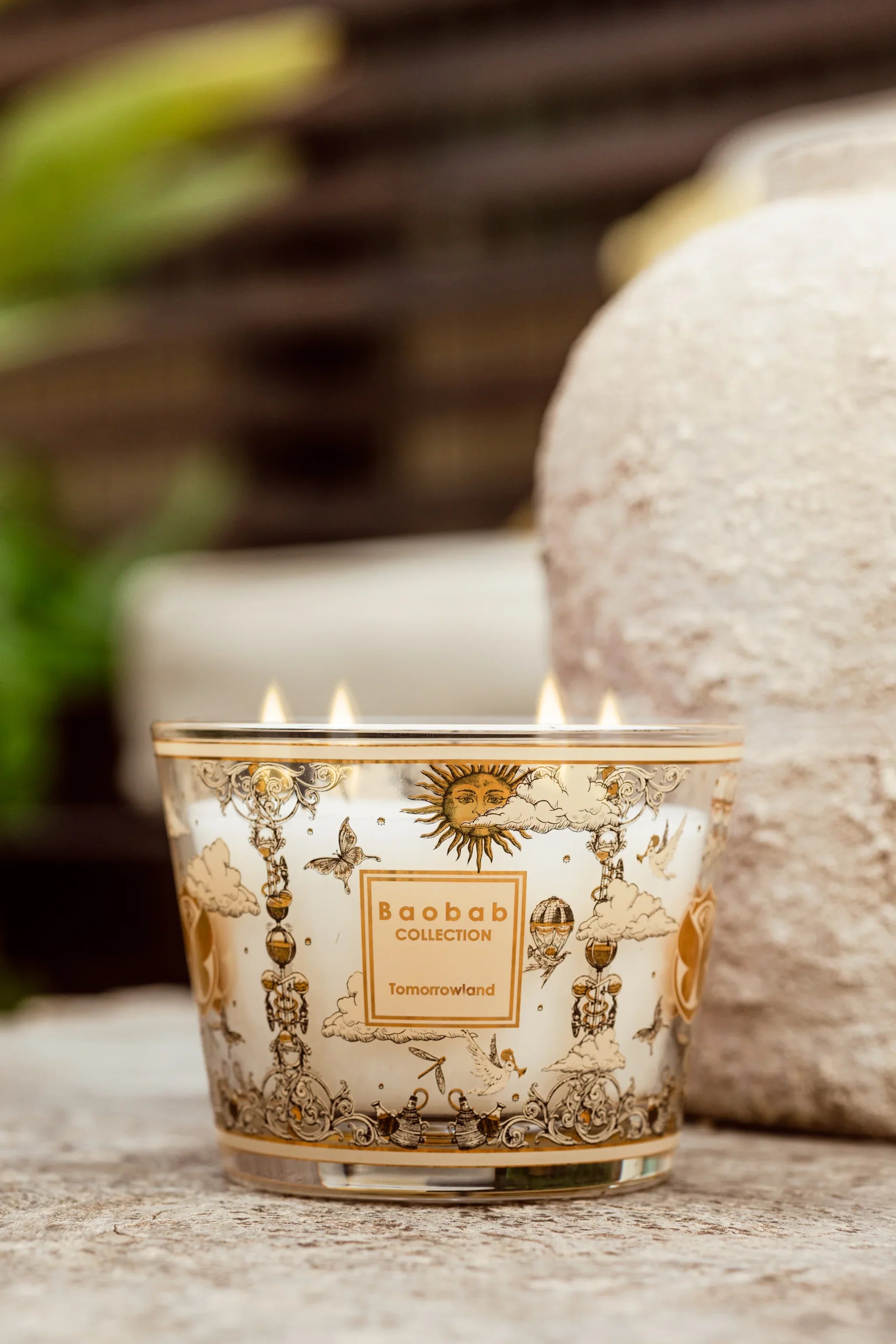 Baobab Collection Tomorrowland scented candle in decorative glass, featuring intricate design and five wicks, outdoors.