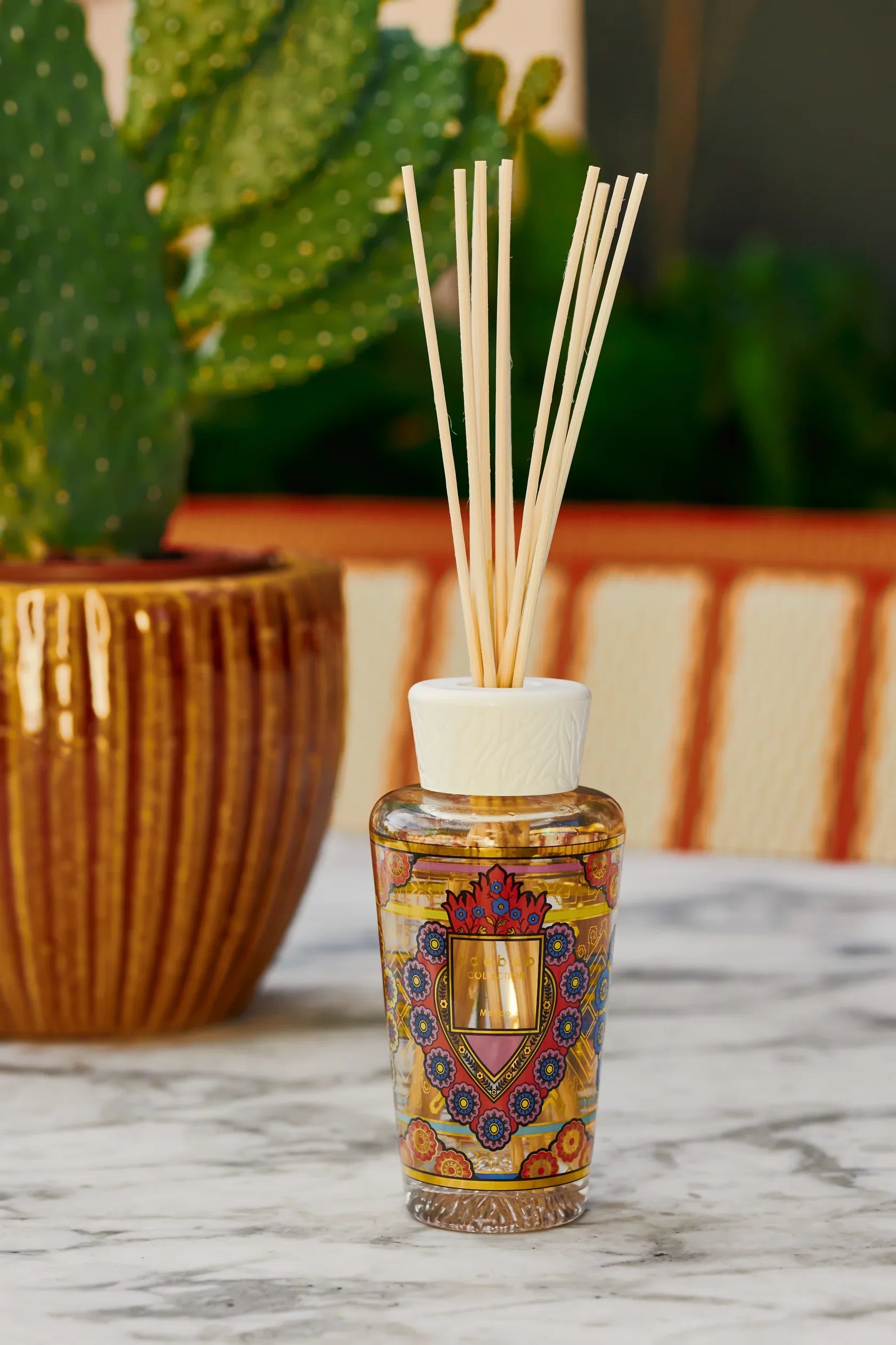 Baobab Collection diffuser 'My First Baobab Mexico' with colorful ex-voto heart design and reed sticks on marble surface.
